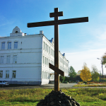 Крест на месте разрушенной церкви Василия Великого (на заднем плане - здание, где располагалось духовное училище)